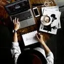 Top view of a creative workspace with laptop, coffee, and hand lettering for design inspiration.